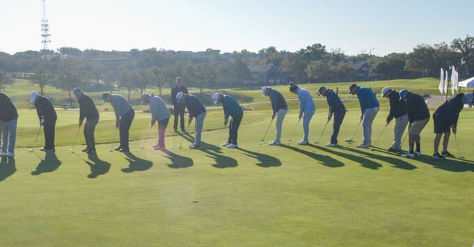 Golfers lined up around a hole for a putting contest